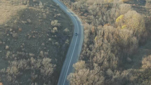 aerial drone footage of the car's movement on a road wheezing between hills and vineyards