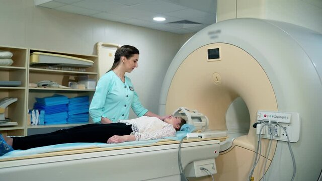 Magnetic resonance image device in hospital. Female patient lying in MRI machine and medical worker controls the procedure. Advanced medicine.