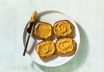 peanut butter spread on bread and a knife on a plate on the table