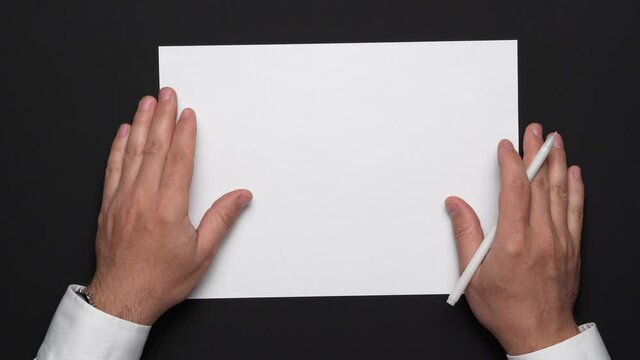 top view of a blank sheet of paper and a businessman's hands on a black table, white shirt and wrist watch