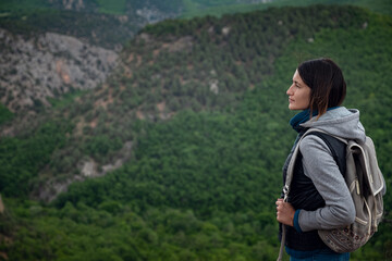 Naklejka premium Young traveling woman on the top of the mountain cliff