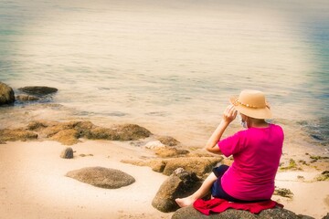 senior woman with hat and medical mask on the beach, prevention against viruses and infections