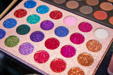 Assortment of different colourful eye shadow palettes in cosmetic store . Palette of shadows for professional make-up . Colorful make-up background. Professional make-up palette .