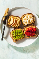 various sandwiches with peanut butter and strawberries, celery, banana and apple on a plate on the table. perfect morning breakfast