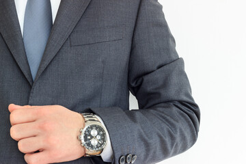 Businessman in gray suit with watch on his wrist. Young caucasian elegant man raised his arm on isolated white background.