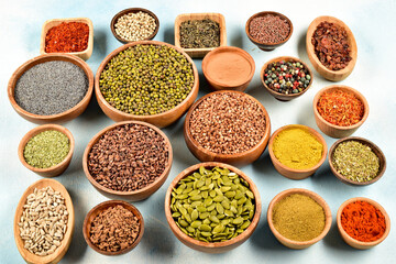 Top view of different kinds of colorful spices in wooden bowls on white surface. - Powered by Adobe