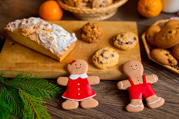 Christmas gingerbread cookies, tangerines, branches of a Christmas tree with garlands on a wooden background. A Christmas background with space for text. Happy Christmas morning.