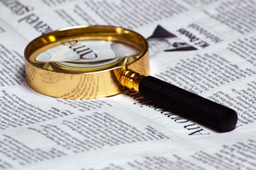 old style magnifying glass lens and newspaper