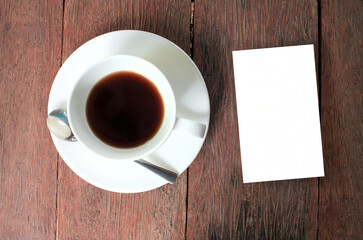 cup of coffee on wooden table with white blank card