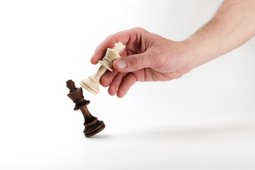 hand holds a chess king piece and defeats another king