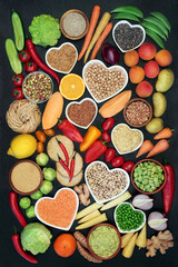 Fototapeta na wymiar Vegan food for a healthy heart concept with foods high in protein, vitamins, lycopene, minerals, anthocyanins, antioxidants, smart carbs & dietary fibre. Ethical eating. Flat lay on dark wood.