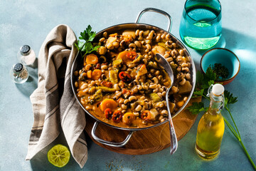 Black-eyed Pea Vegan Chili in a metal pan on a wooden stand on a blue background