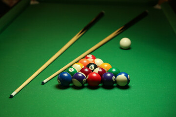 billiard background with color pool balls and cues on green table