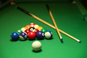 billiard background with color pool balls and cues on green table