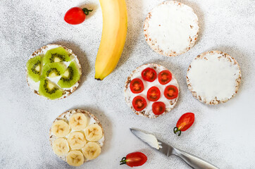 Fototapeta premium Vegetarian food crispbreads with curd cheese, cherry tomato, slices kiwi and banana. A hearty and healthy snack and nutrition in summer lifestyle