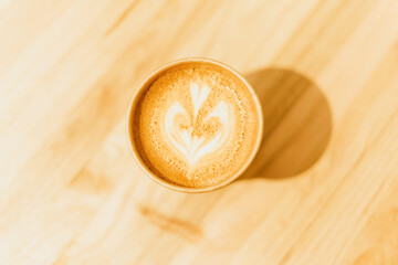 coffee cup latte art image of a coffee with milk on a wooden table in the bar of a coffee shop