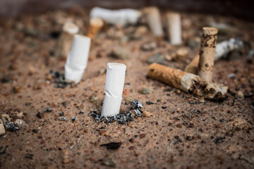 Cigarette butts in yellow sand. Problem of humanity. Cigarette smoking, bad habit. Nicotine...