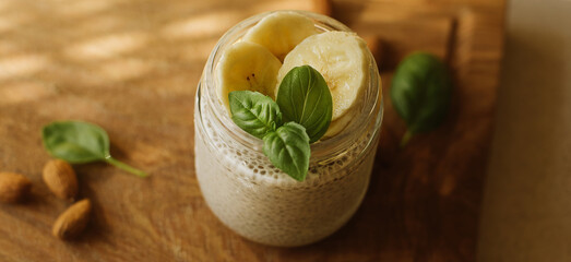 Vegan Chia Pudding with Banana and almond on wooden background. Vegan, morning, breakfast, healthy eating concept. Banner for website