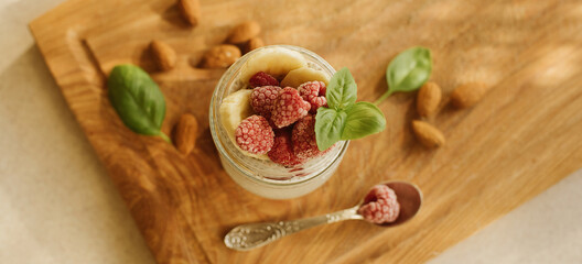 Vegan Chia Pudding with Frozen raspberry, Banana and almond on wooden background. Vegan, morning, breakfast, healthy eating concept. Banner for website. top view