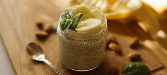 Vegan Chia Pudding with Banana and almond on wooden background. Vegan, morning, breakfast, healthy eating concept. Banner for website