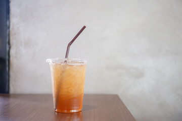 Peach ice tea in plastic cup on wooden table