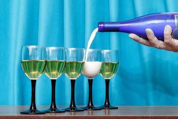A man pours wine and milk into glasses.