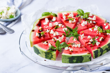Watermelon pizza with feta cheese and herbs on a table