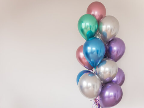 multicolored balloons on the background of a light wall. left-oriented image