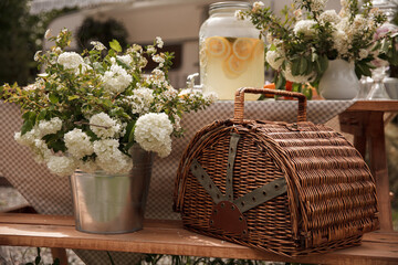 Picnic basket with fruits. Picnic in the nature. White flowers in a pot