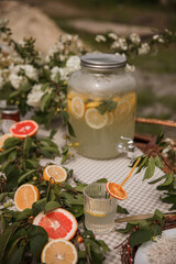 Lemonade in glass jug on wooden table outdoors. Summer refreshing drink.