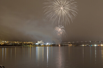 Beautiful firework on night sky in tromsoe city with bridge, cathedral and colorful reflection on the cold fjord water surface on new years eve