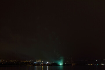 Beautiful firework on night sky in tromsoe city with bridge, cathedral and colorful reflection on the cold fjord water surface on new years eve