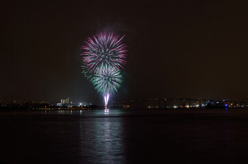 Beautiful firework on night sky in tromsoe city with bridge, cathedral and colorful reflection on the cold fjord water surface on new years eve