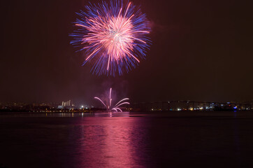 Beautiful firework on night sky in tromsoe city with bridge, cathedral and colorful reflection on the cold fjord water surface on new years eve