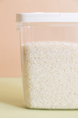 Plastic transparent container with rice on a green background.