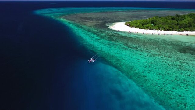 Banca boat leaving Mantigue Island in the Philippines, aerial