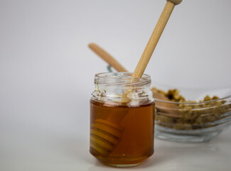 Honey and walnuts on a white background. Wooden stick for honey. It is naturally the healthiest