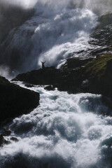 Girl dancing under huge waterfall.