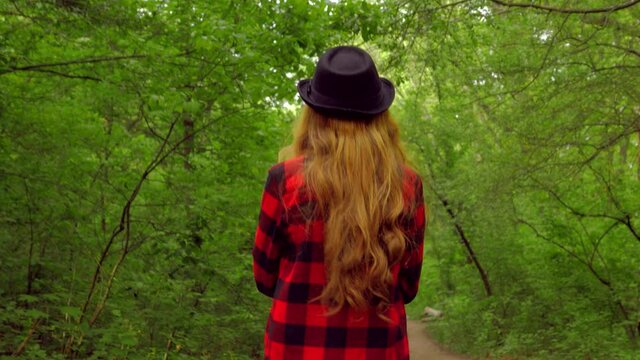 girl in a red shirt and hat walks in a summer park