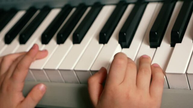 Concept on the theme of a child playing a musical instrument. Close-up of children's hands playing the keys of a piano, learning to play the piano