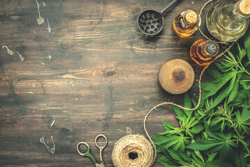 Cannabis CBD oil bottles and green plant leaves on dirty wooden table background.