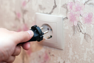 A man's hand plugs the cord into a power outlet.