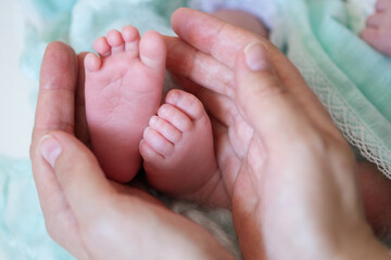 Obraz na płótnie Canvas newborn baby feet in the hands of mother