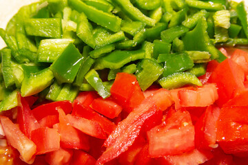 chopped green peppers and tomatoes on a table.