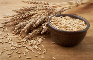 Уши пшеницы и чаша зерна пшеницы на коричневом деревянном фоне
