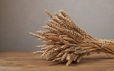 Уши пшеницы и чаша зерна пшеницы на коричневом деревянном фоне