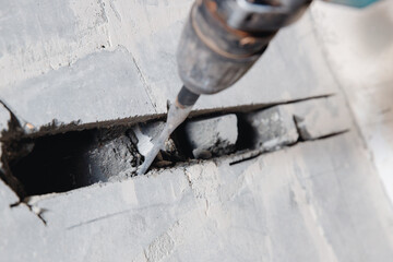 Builder worker man using jackhammer to drill into construction wall for duct for air conditioning...