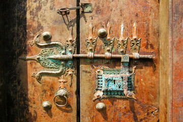 Kerala, India. Very old wooden door with a metal turquoise trident as a lock.