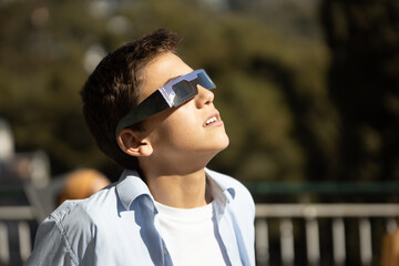 impressed teenager looking at a sun eclipse with eclipse glasses - obrazy, fototapety, plakaty