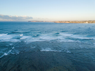 Aerial view of wave water with clear blue sky.